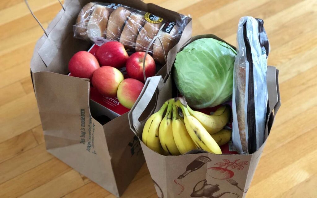 2 sacchetti di carta con spesa di frutta e verdura e pane